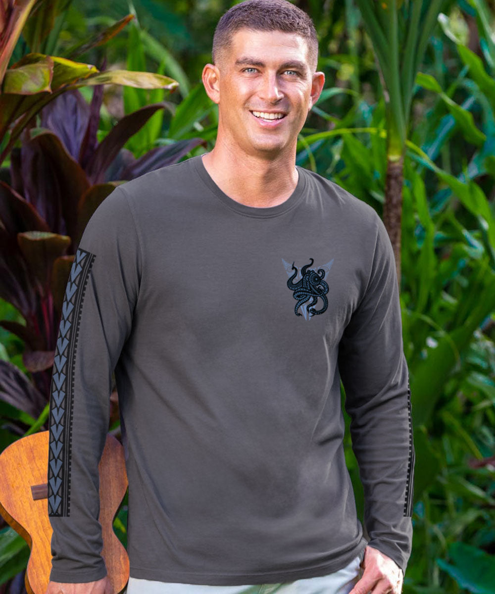 A man wearing a gray long-sleeve shirt with a small blue octopus design on chest and blue designs on the sleeves with greenery in the background. View 3