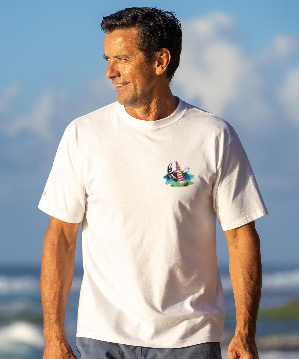 Man wearing a white t-shirt with a graphic design against a blue sky and ocean background View 3