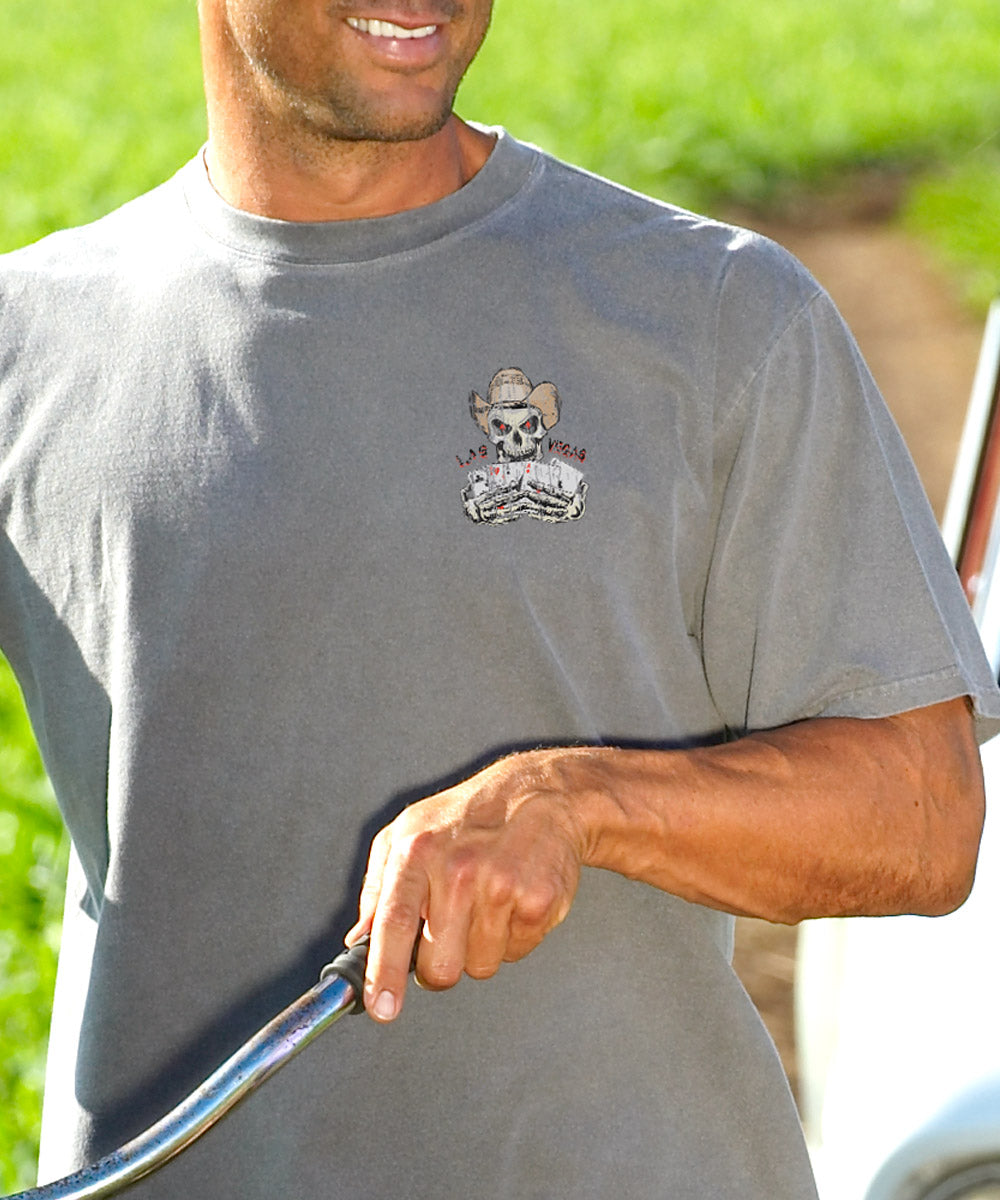 Man wearing a gray t-shirt with a logo, holding a railing outdoors. View 3