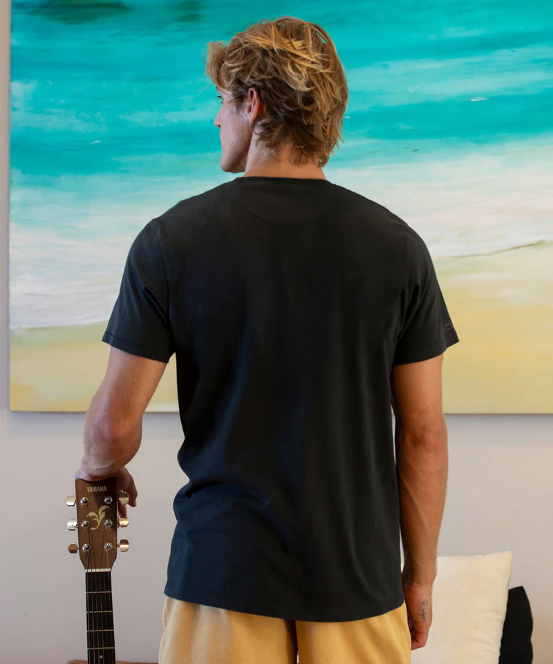 Man wearing a black t-shirt standing in front of a large abstract painting. View 3