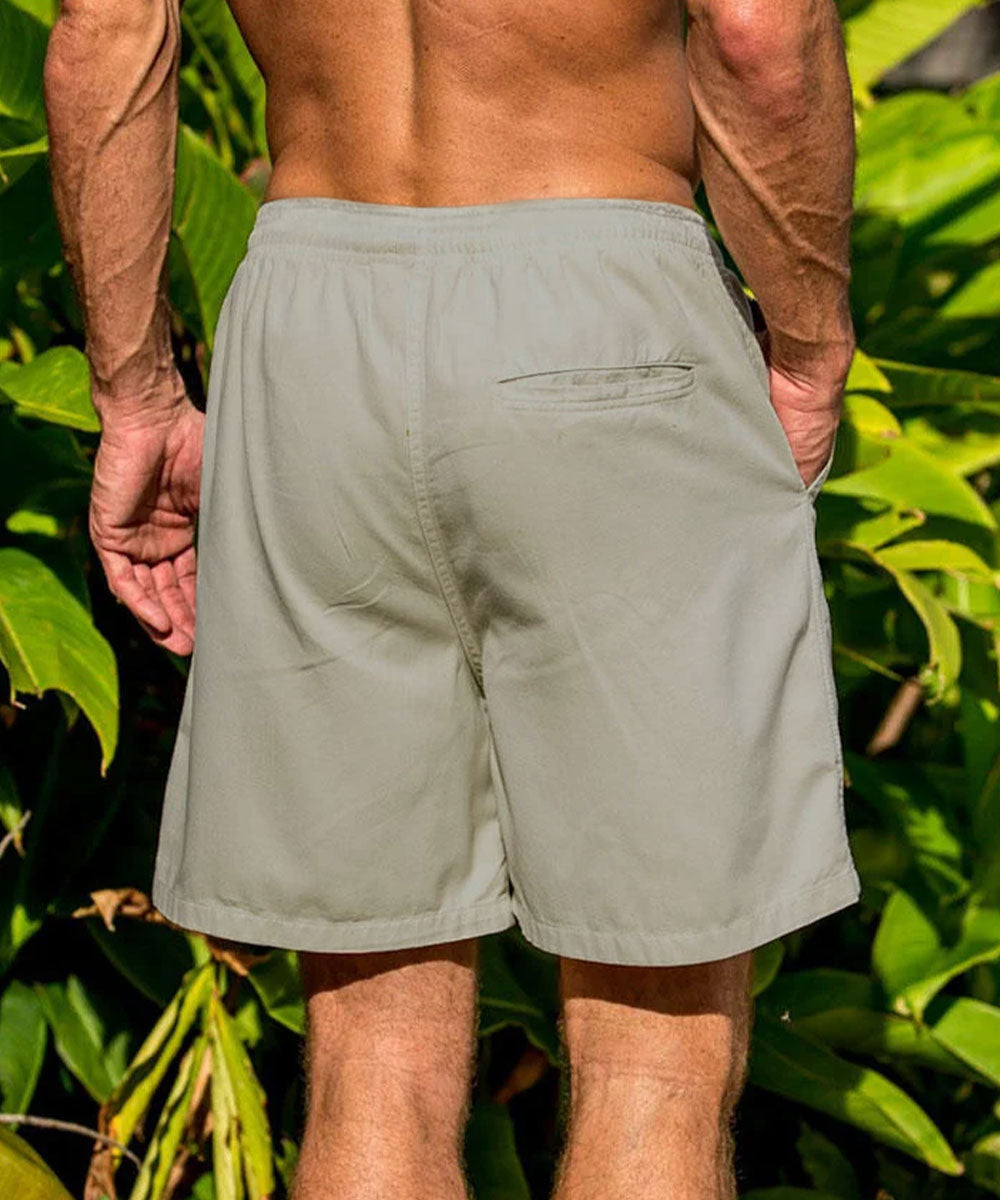 A man wearing light khaki shorts, shown from the back against a foliage background View 3