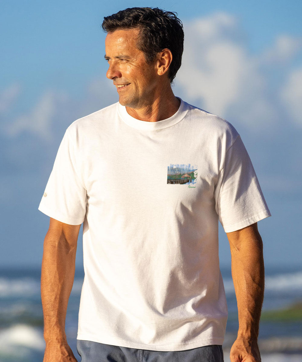Man wearing a white t-shirt with a small graphic on a beach View 3