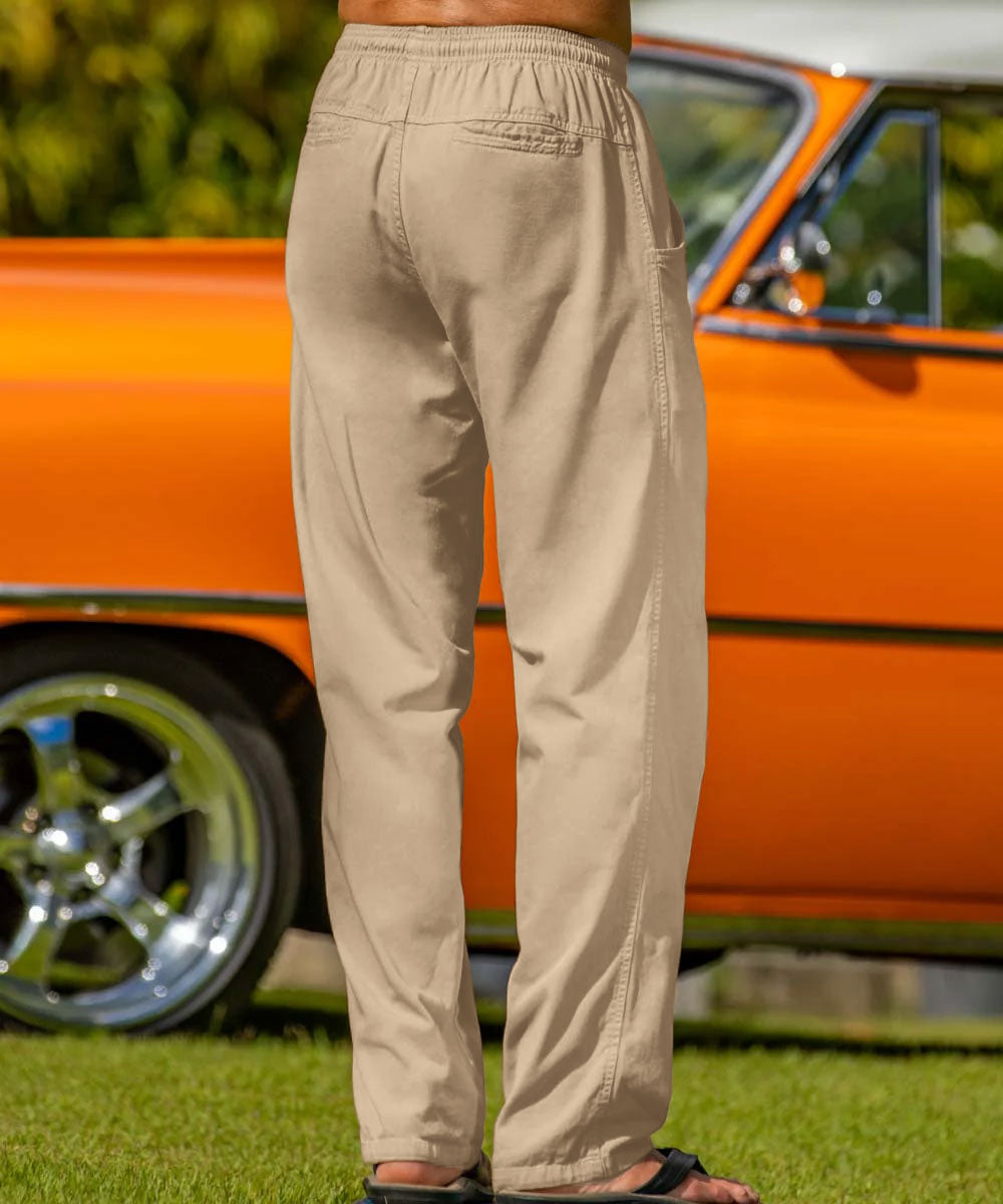 A man standing in front of an orange vintage car, wearing beige cotton twill pants, featuring the back pockets. View 3