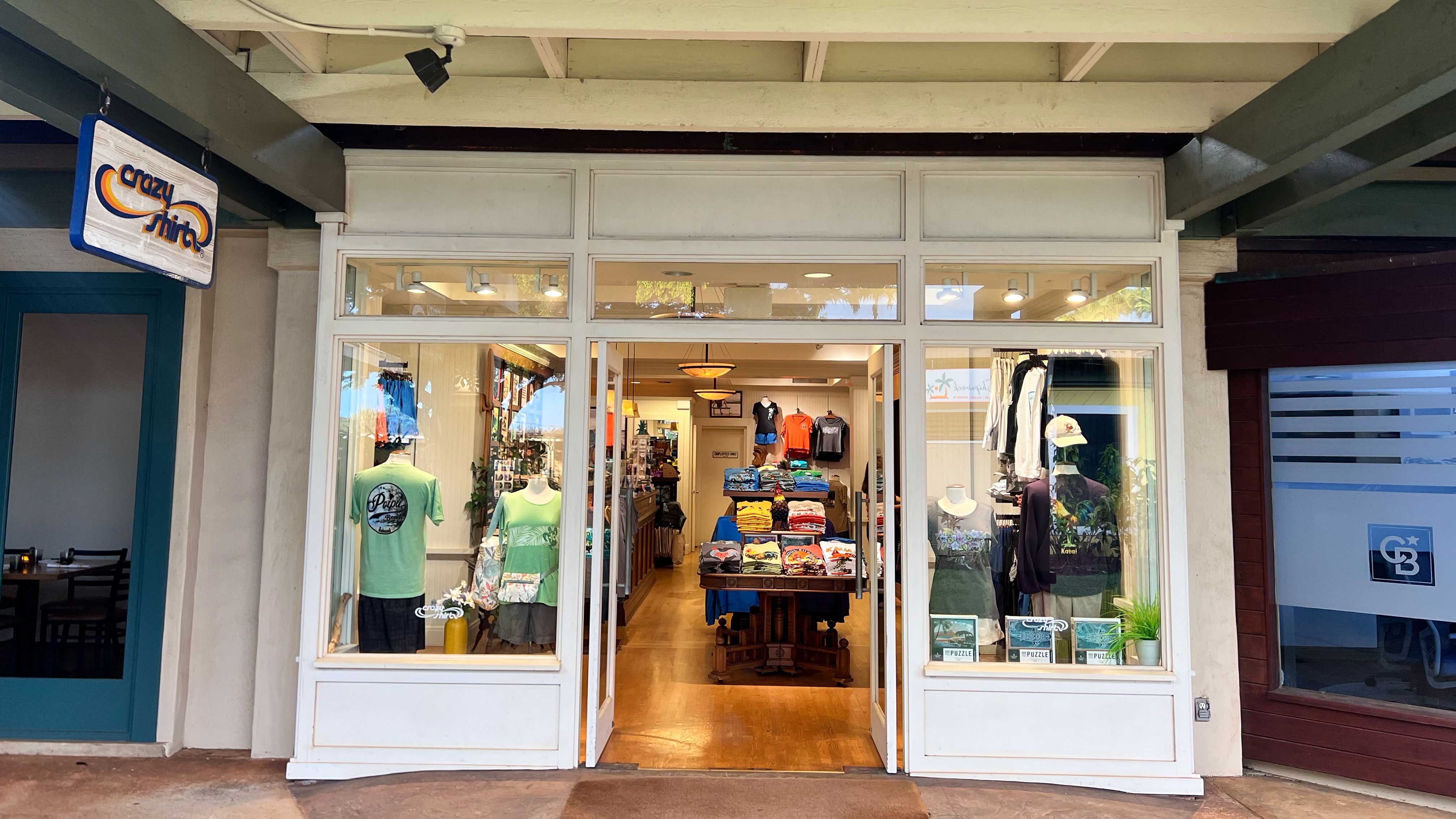 Poipu torefront with glass doors and interior display, featuring various items and clothing.