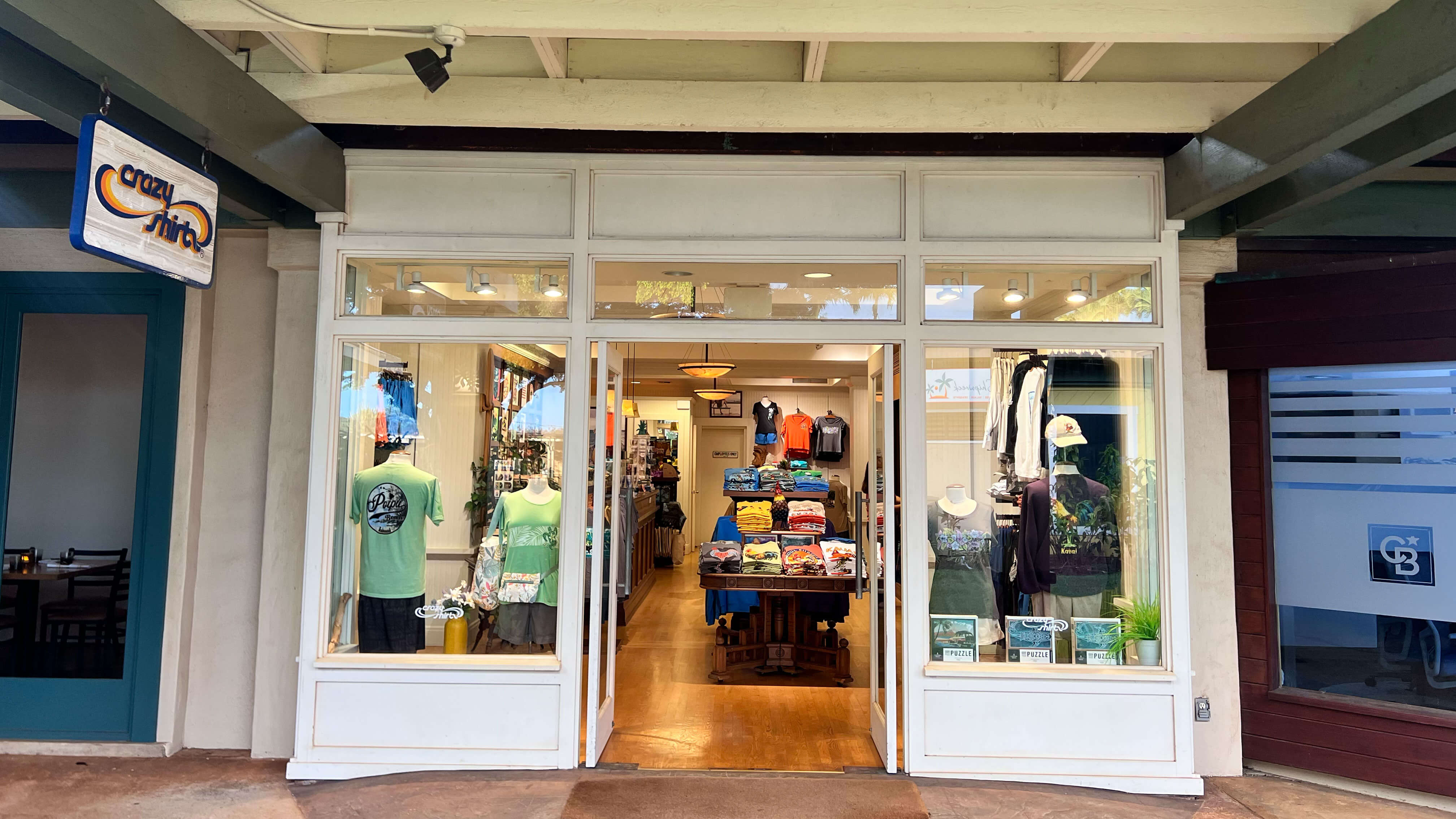 Poipu storefront with glass doors and interior display, featuring various items and clothing.