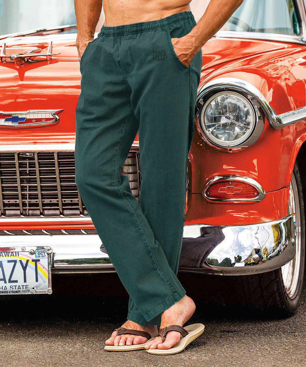 A person standing in front of a red car wearing dark green twill pants with an elastic drawstring waistband. View 2