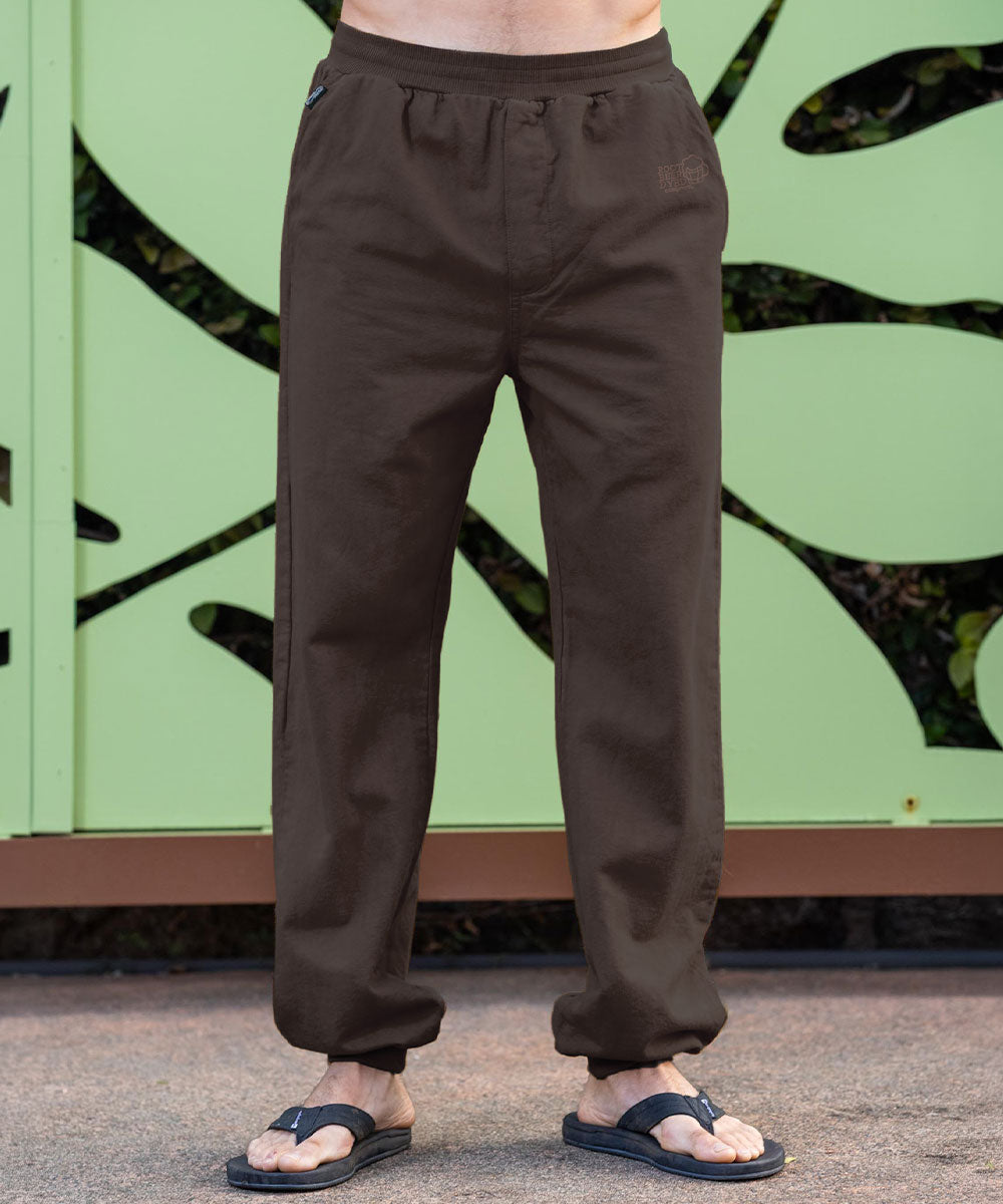 A person standing in front of a gate wearing brown pants View 2