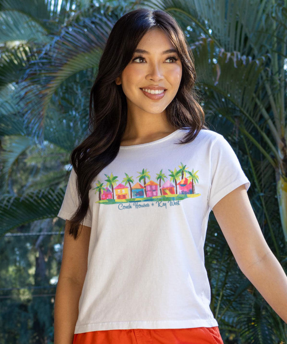 Woman wearing a white t-shirt with colorful graphic design in front of green foliage View 2