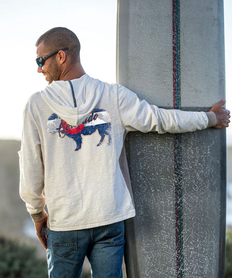 Man wearing a hoodie with a dog graphic, leaning against a concrete wall. View 2