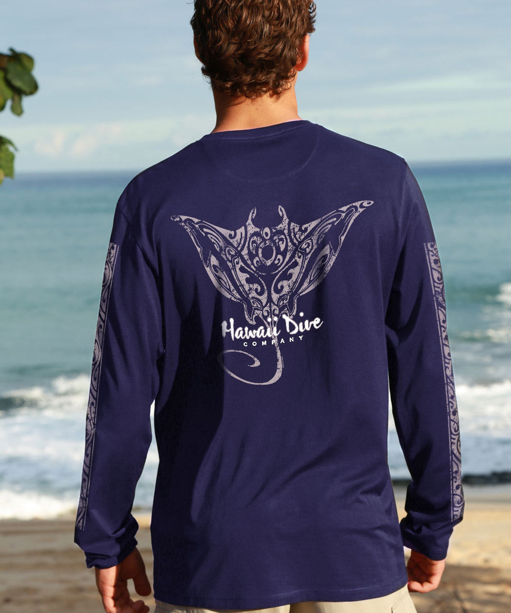 Person wearing a navy blue shirt with a manta ray design on a beach. View 2