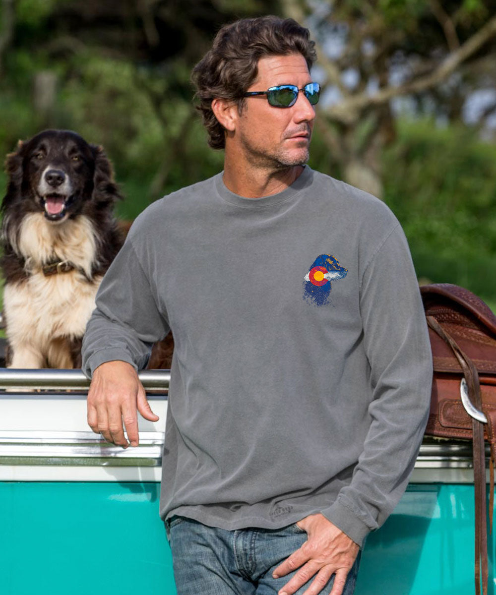 Man wearing a gray long-sleeve shirt with a logo, standing next to a dog by a turquoise vehicle. View 3
