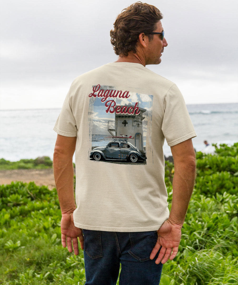 Man wearing a t-shirt with 'Laguna Beach' design, standing by the ocean. View 2
