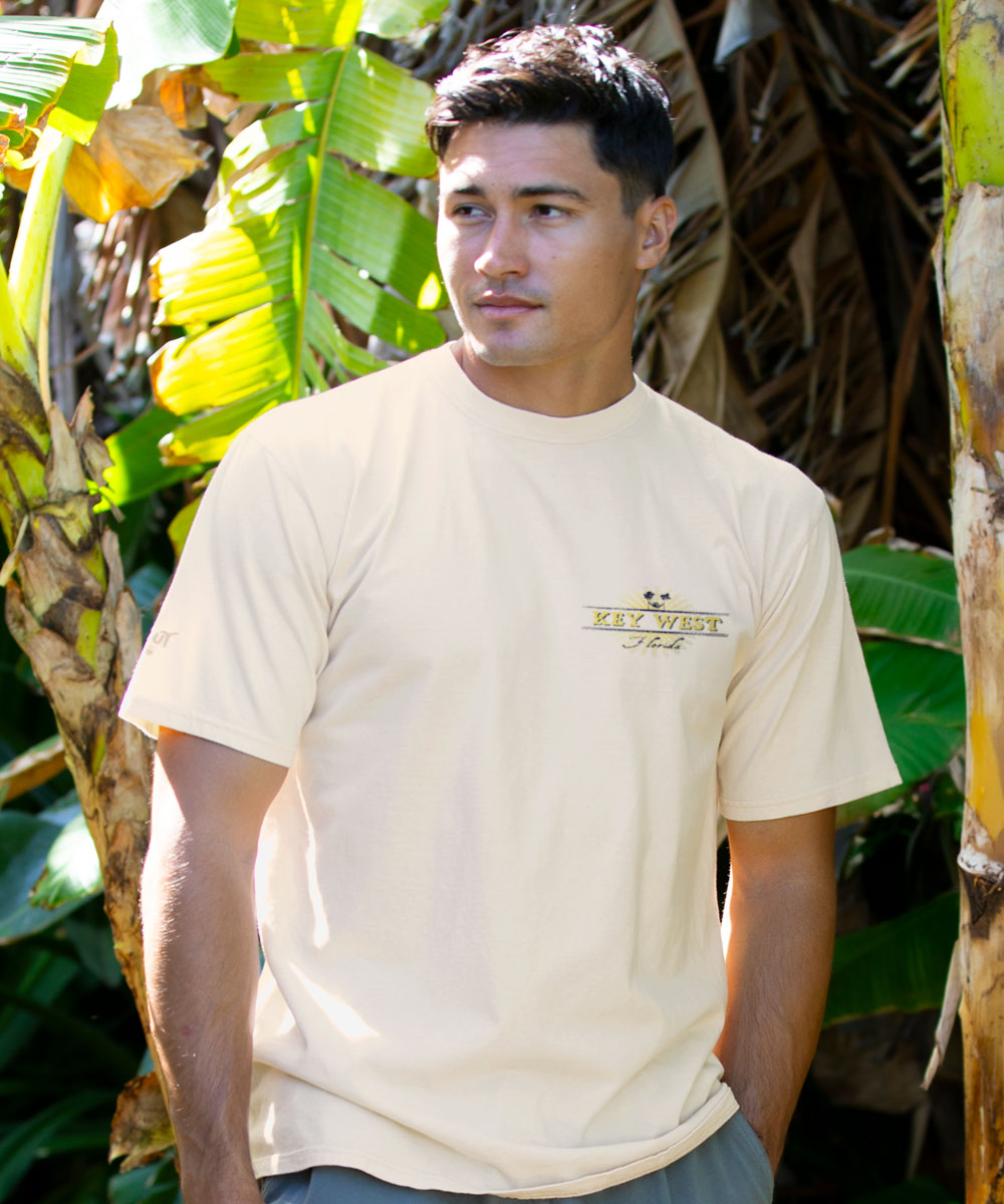 Man wearing a white t-shirt with a logo in a tropical setting View 3