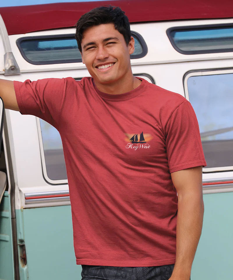 Man wearing a red t-shirt with a key west logo standing next to a vintage van. View 3