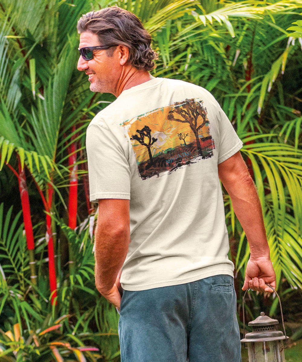 Man wearing a t-shirt with a graphic design standing in a tropical setting. View 2
