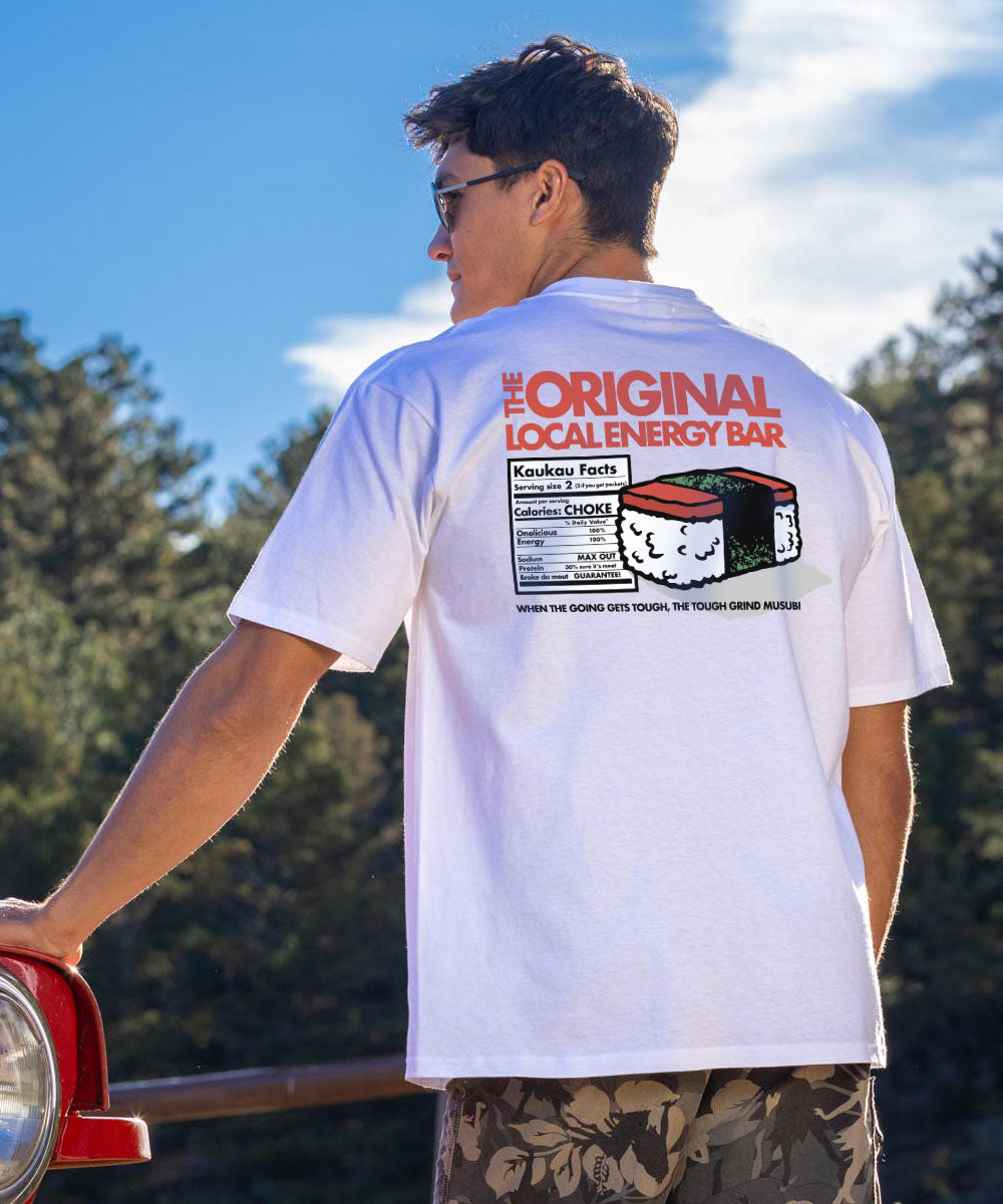 Man wearing a white shirt with a graphic design on it standing in front of a forest with blue skies View 2