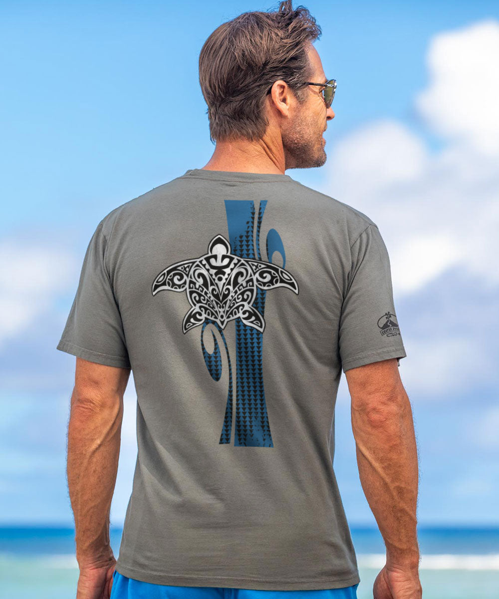 Man wearing a gray t-shirt with a graphic design on the back, standing on a beach. View 2