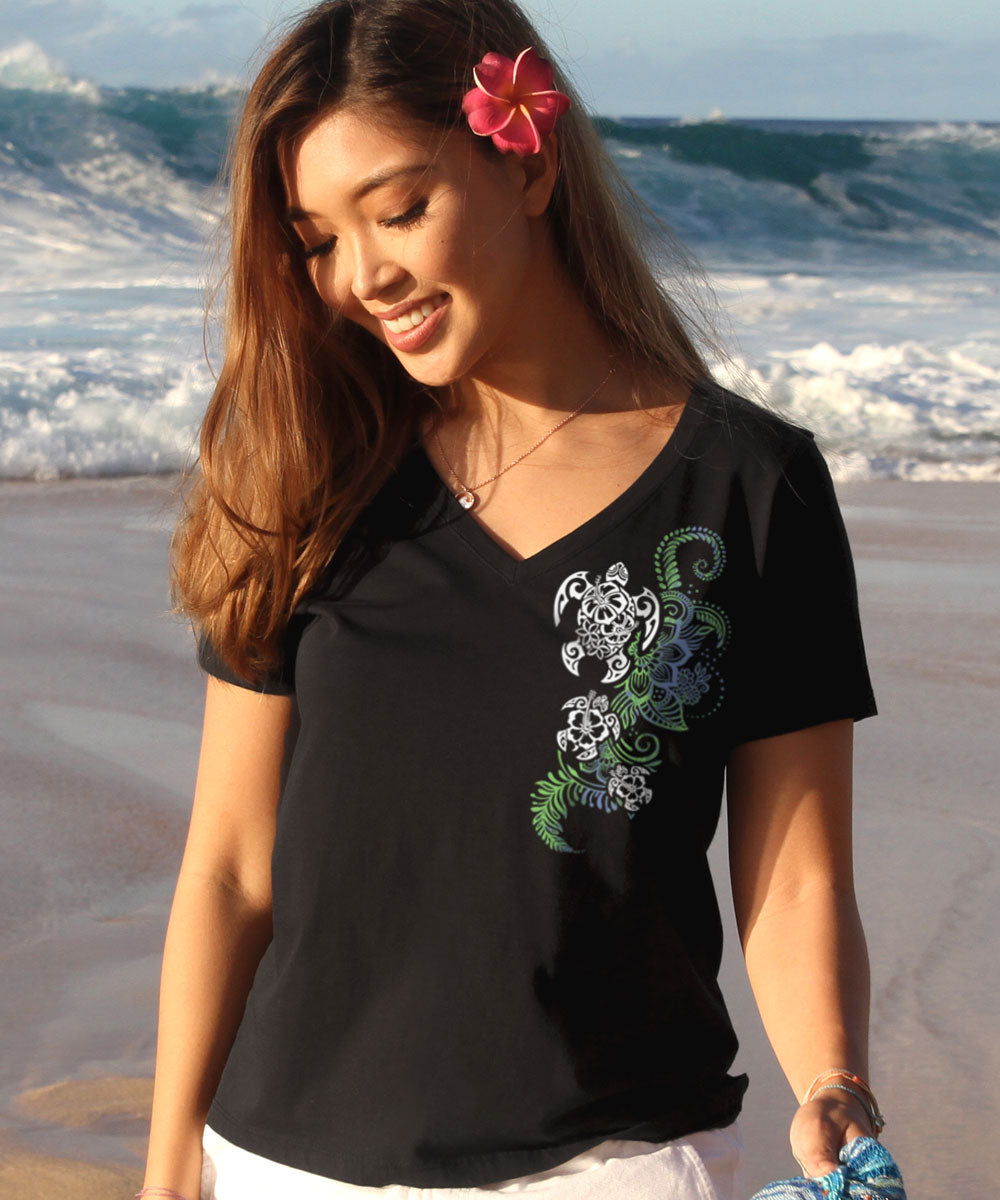 Woman wearing a black v-neck shirt with a turtle design on the front standing in front of the ocean View 2