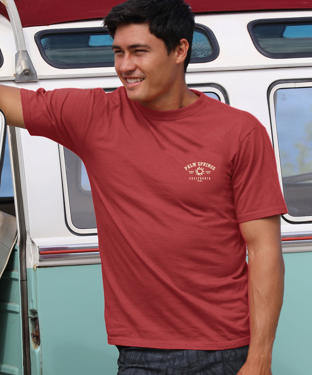 Person wearing a red t-shirt with a logo, standing in front of a vintage van. View 3
