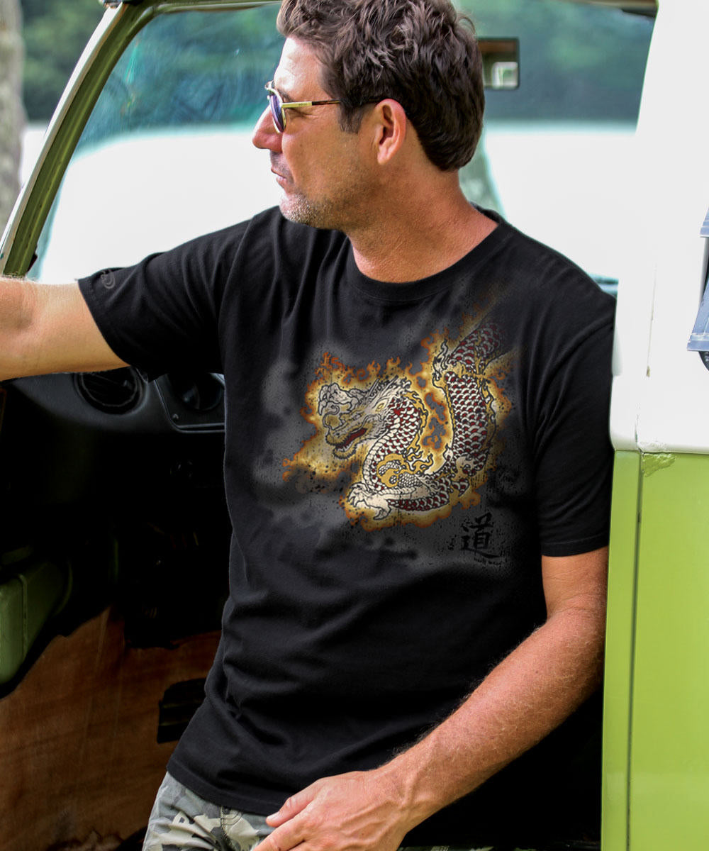 Man wearing a black t-shirt with a dragon design, standing next to a green vehicle. View 2