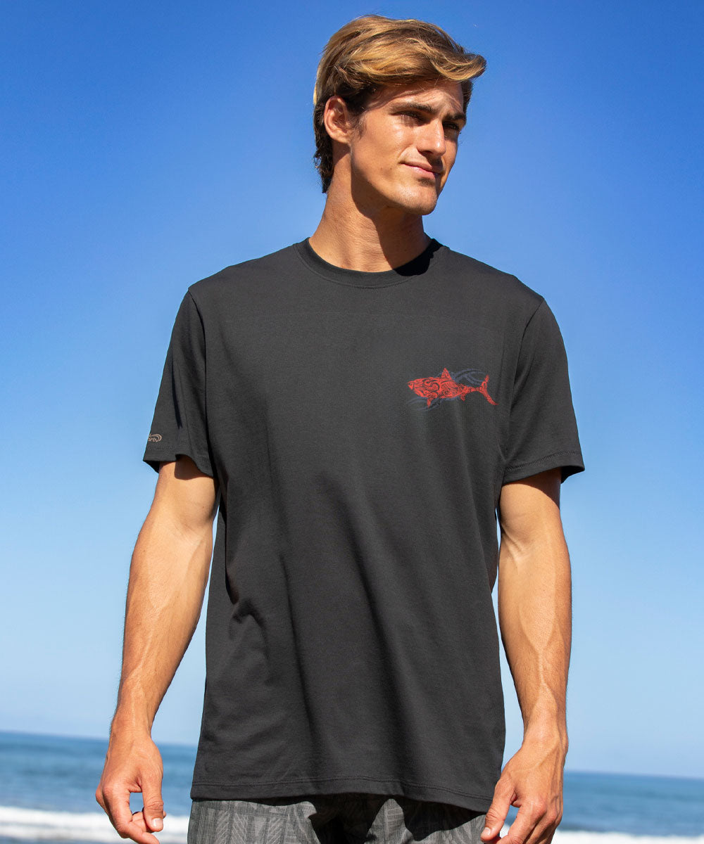 Man wearing a black t-shirt with a red shark logo on a beach View 3