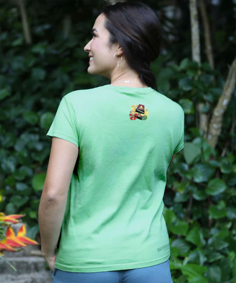 Woman facing away from the camera, wearing a light green t-shirt with a small logo on top middle area in a natural setting. View 3