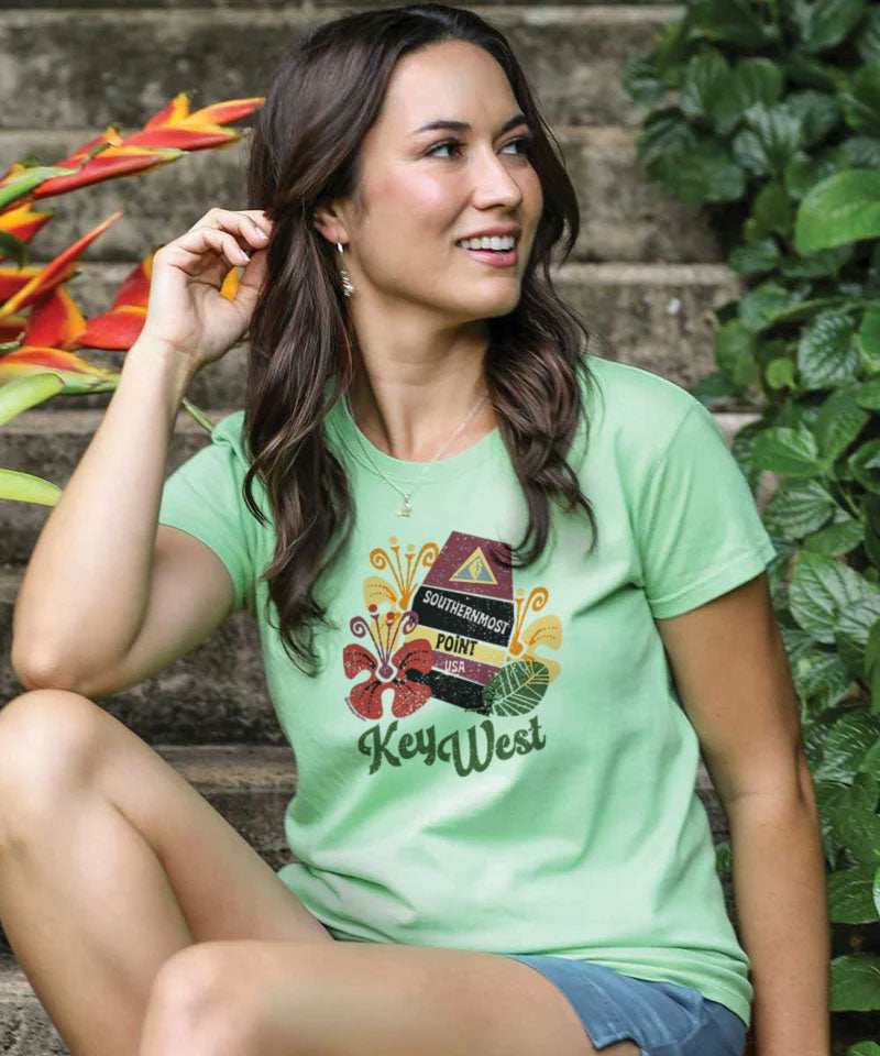 Woman wearing a light green scoop neck t-shirt with a Key West design on the center chest, sitting outdoors. View 2