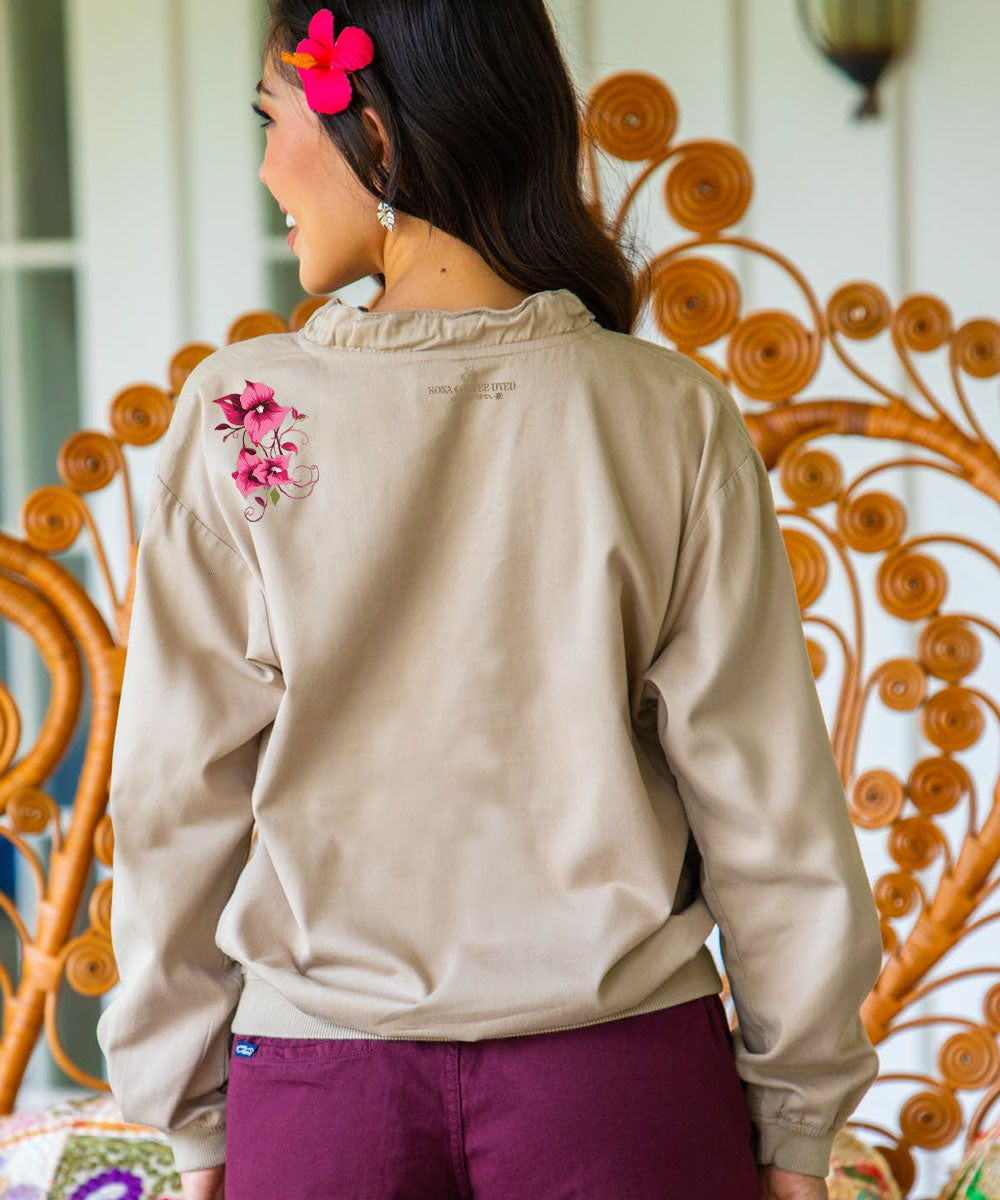 A woman wearing a long sleeve lightweight pullover with pink flowers design on left shoulder, and maroon shorts. View 3