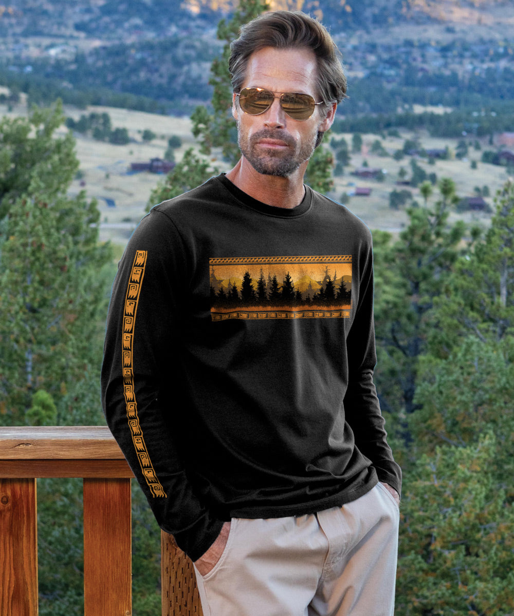 A man wearing sunglasses and a long sleeve jet black Pima t-shirt with a mountain view design, standing on a balcony with a scenic landscape in the background. View 2