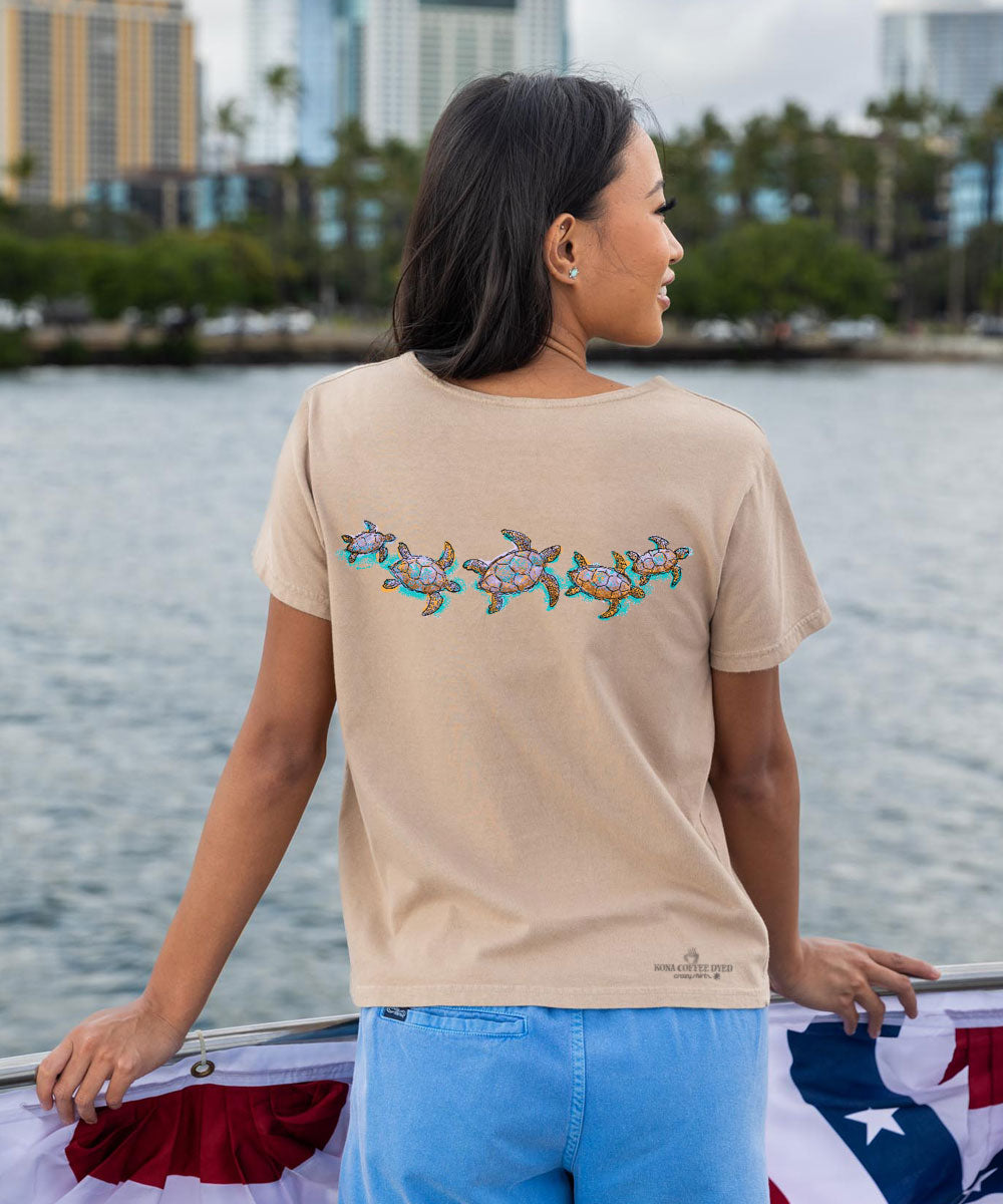 woman wearing a beige t-shrit with a band of turtles printed on it View 3