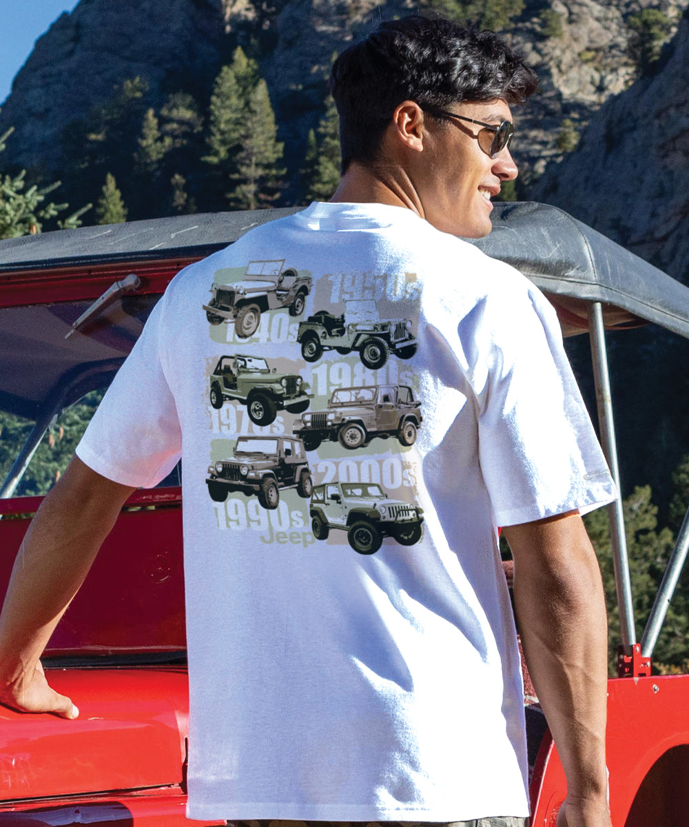 A person wearing a white short sleeve crewneck T-shirt with a graphic of a Jeep Wrangler on the back, standing near a red vehicle. View 2