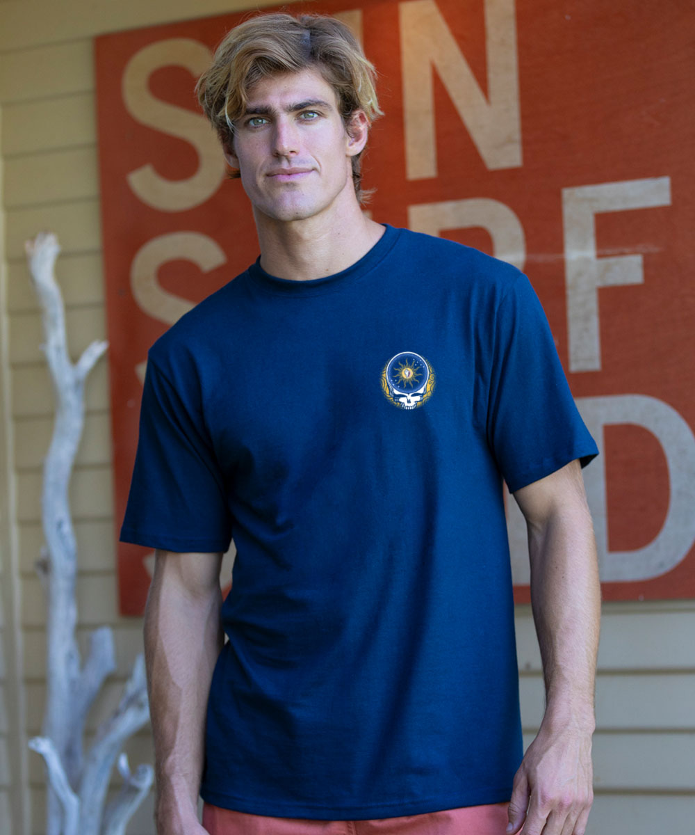 Man wearing a navy blue t-shirt with a logo in front of a red sign with white letters. View 3