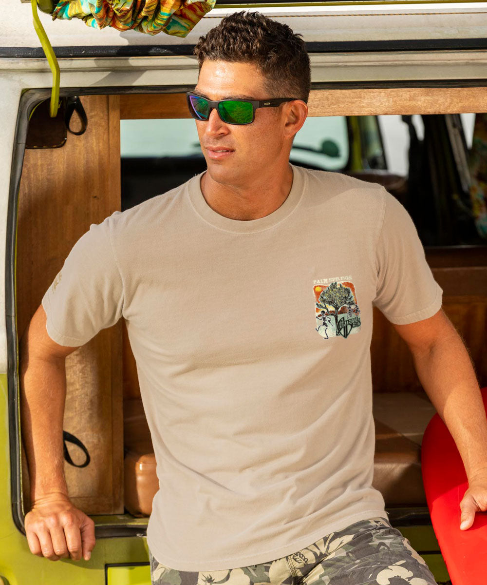 Man wearing a beige t-shirt with a graphic design, sitting inside a vehicle. View 3