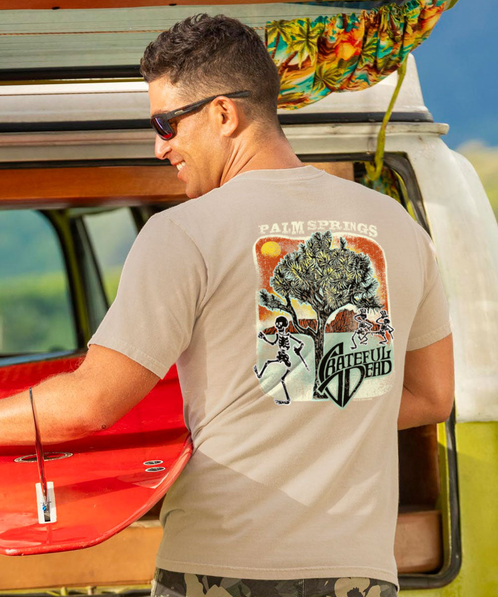 Man wearing a t-shirt with a graphic design, standing next to a colorful van. View 2