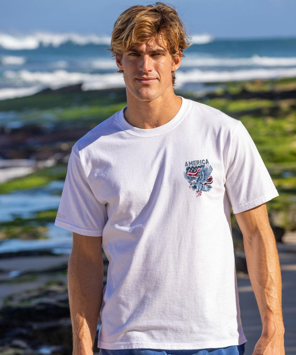 Man in white America t shirt in front of ocean View 3