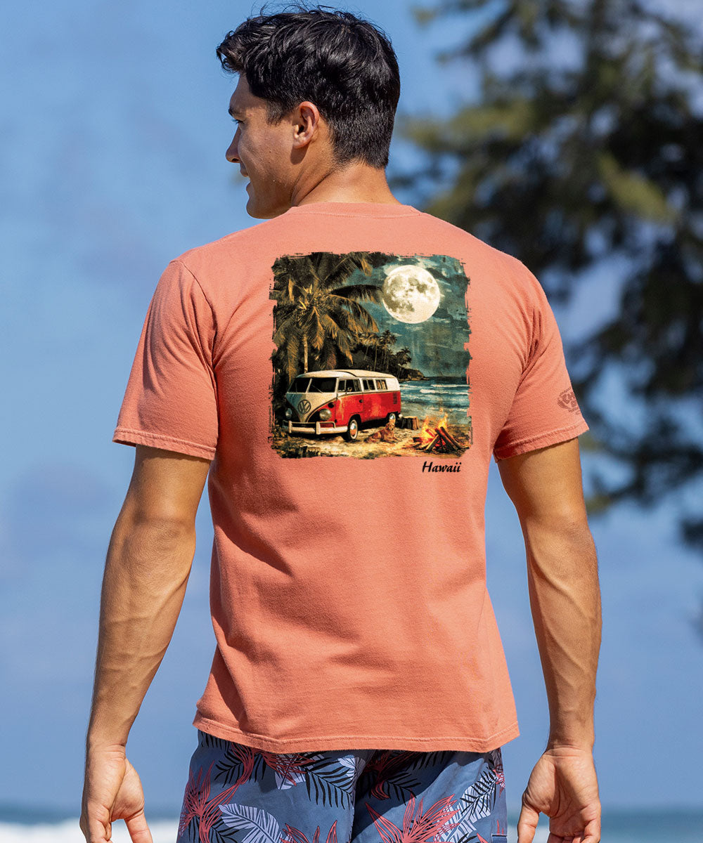 A man wearing a brown short sleeve crewneck t-shirt with a graphic of a Volkswagen van camping near a palm tree and moonlit sky. View 2