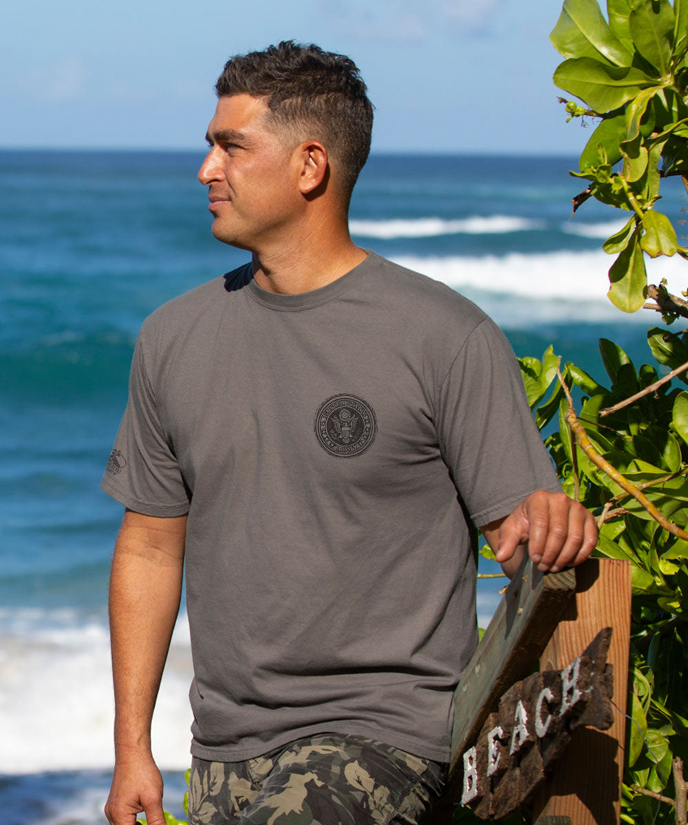 Man wearing a gray short sleeve shirt standing by the beach View 3