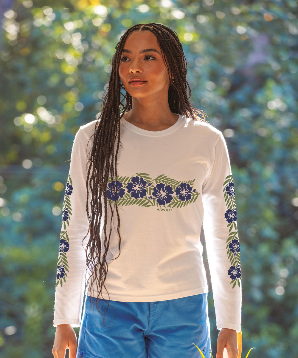 A woman wearing a white long sleeve crewneck t-shirt with a floral band design in blue colors on the sleeves. View 2