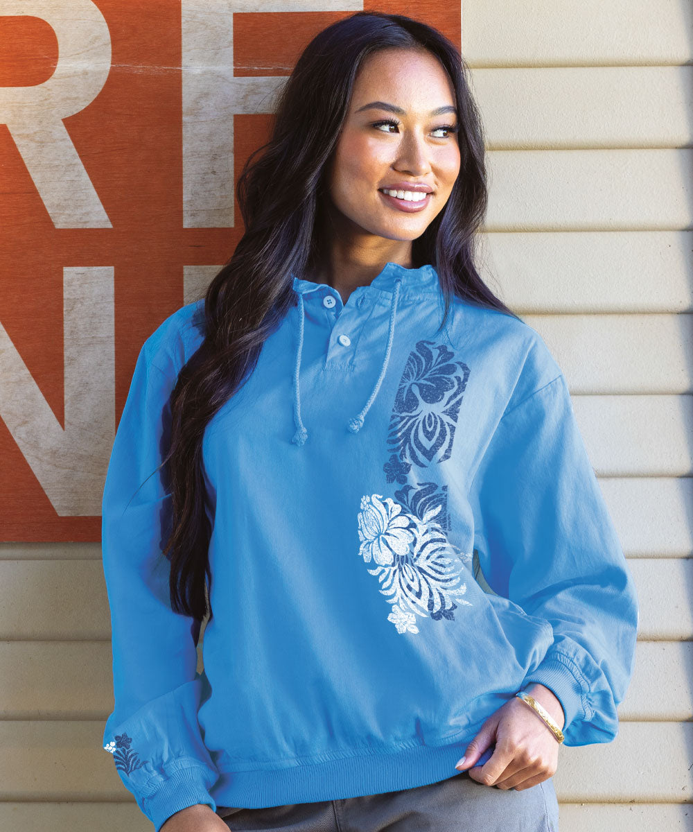 A woman smiling and wearing a blue long sleeve lightweight pullover with a graphic design in the front. View 2