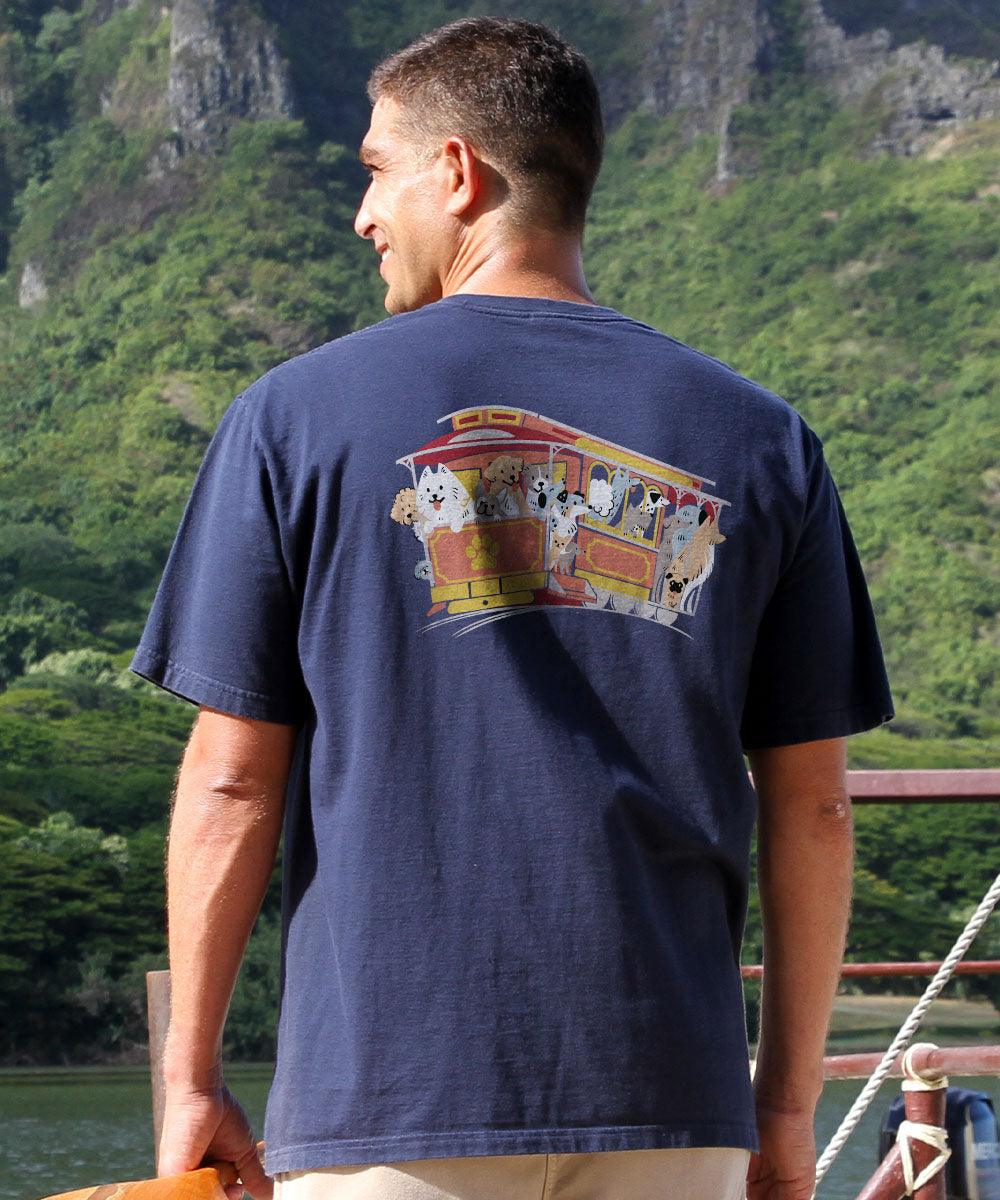 Man wearing a navy blue t-shirt with a colorful graphic on the back, standing outdoors with greenery in the background. View 3