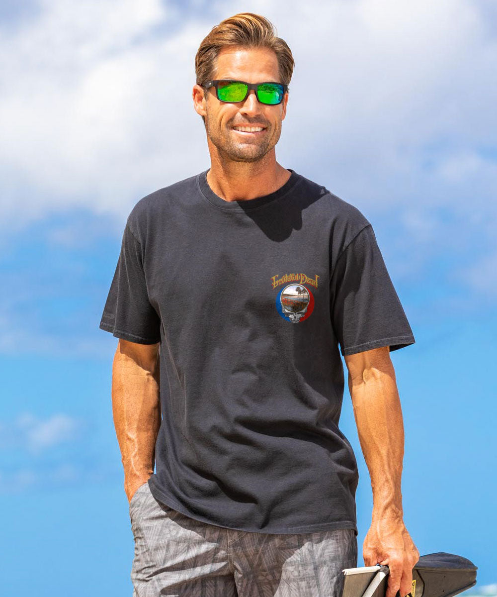 Man wearing a black t-shirt with a logo outdoors against a blue sky. View 3