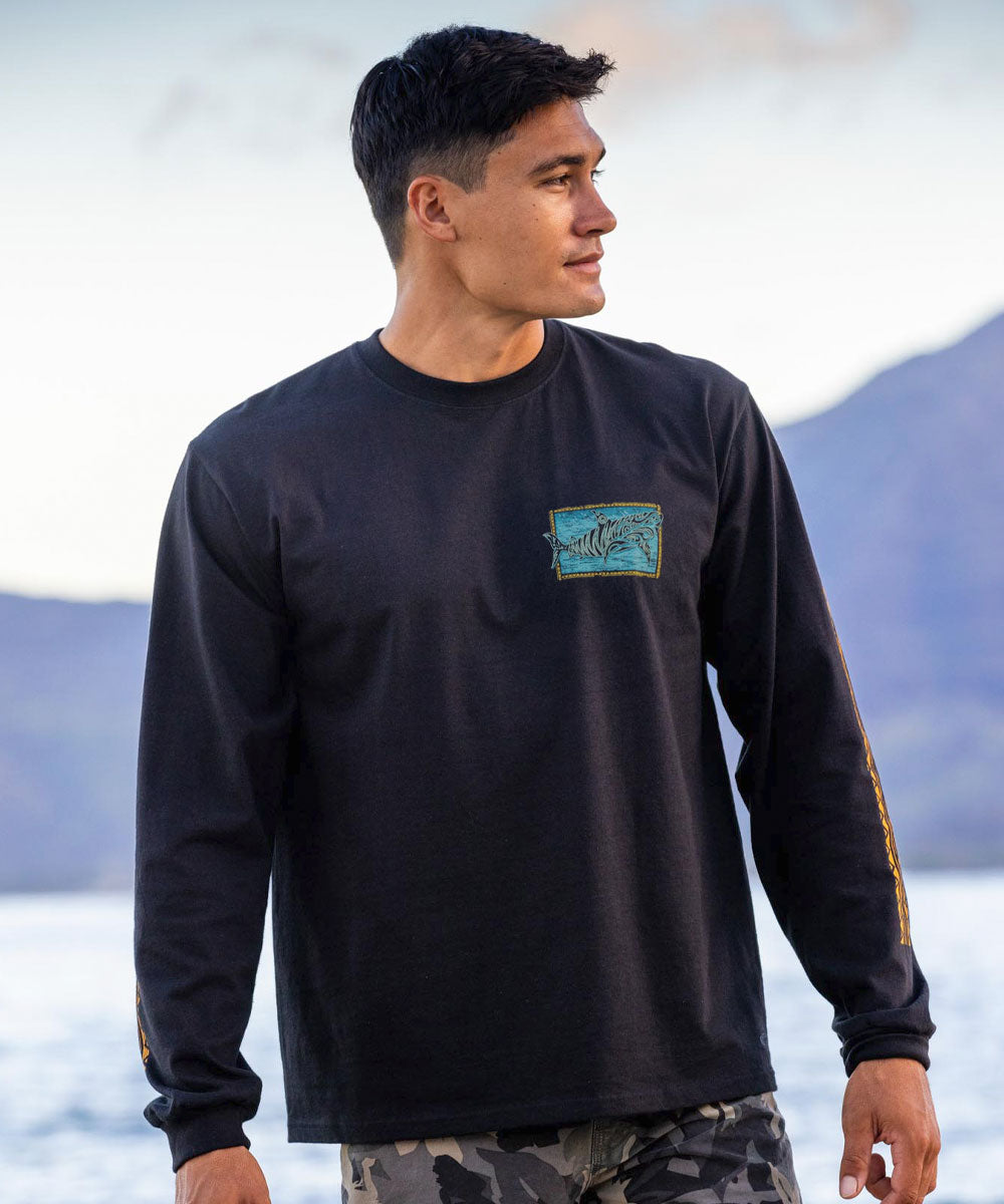 Man wearing a black long-sleeve shirt with a shark pocket design in front of a mountainous landscape. View 3