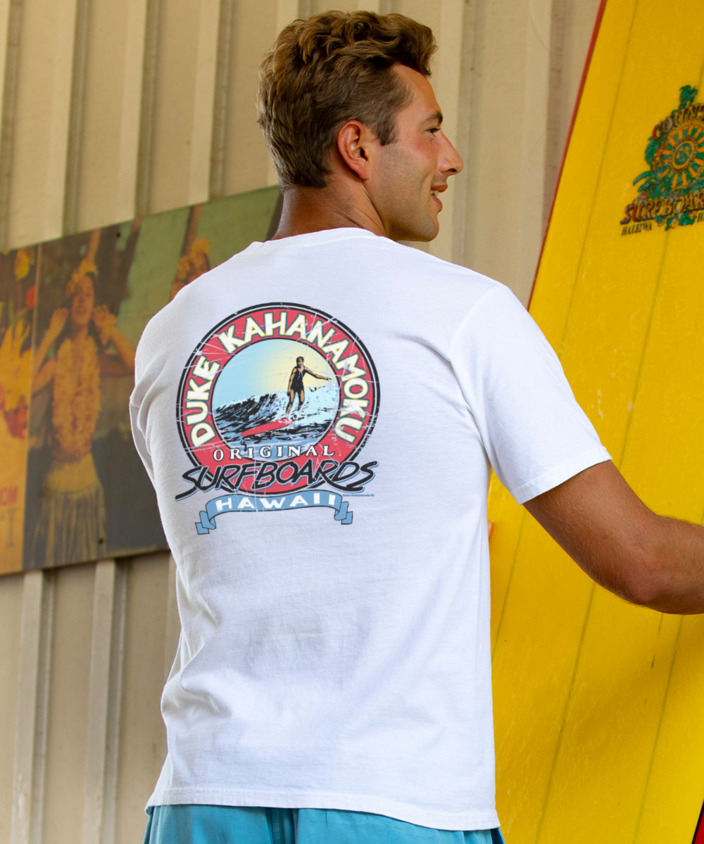 Man wearing a white t-shirt with a Duke Kahanamoku logo, holding a yellow surfboard. View 2