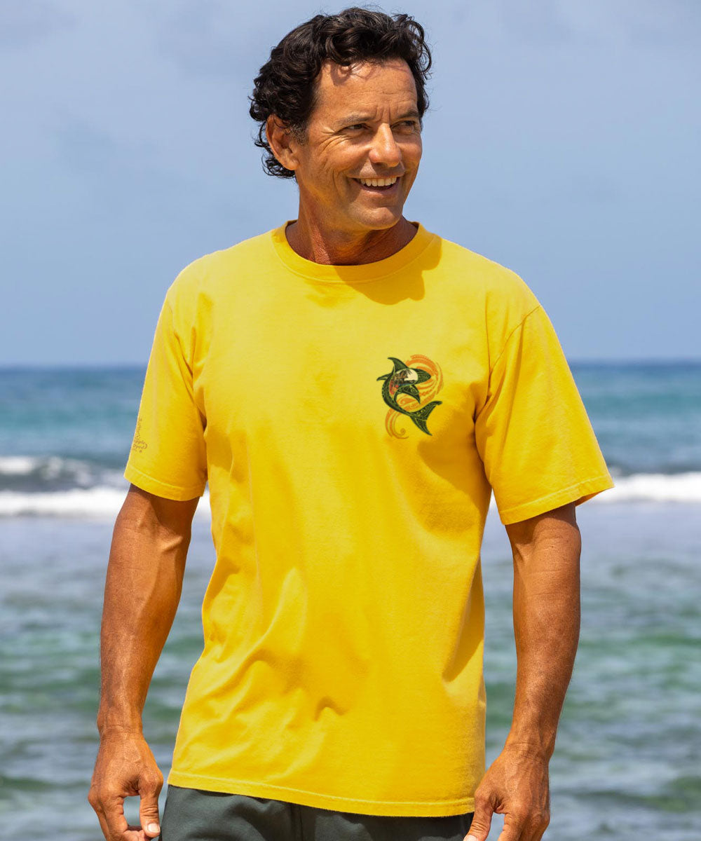 Man wearing a yellow t-shirt with a shark design on the pocket at a beach View 3