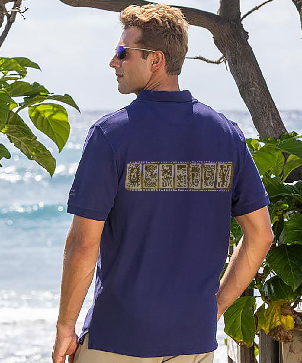 Man wearing a navy blue polo shirt with a design on the back, standing outdoors with greenery and water in the background. View 3