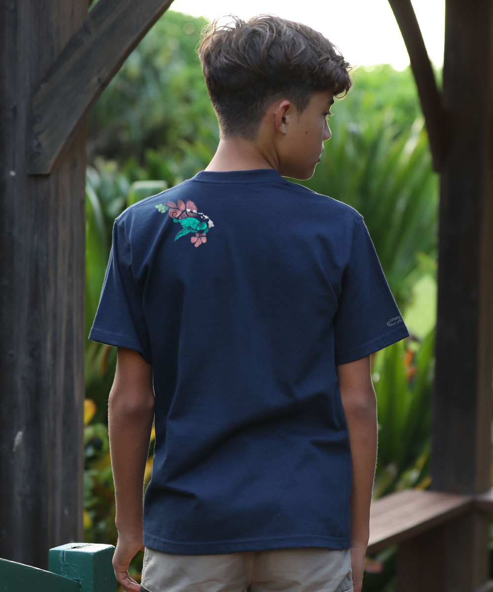 Person wearing a blue t-shirt with a floral design on the back, standing outdoors. View 3
