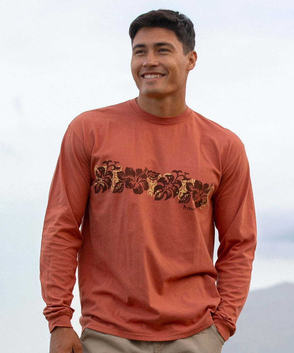Man wearing a rusty brown long-sleeve shirt with a floral band design against a clear sky. View 2