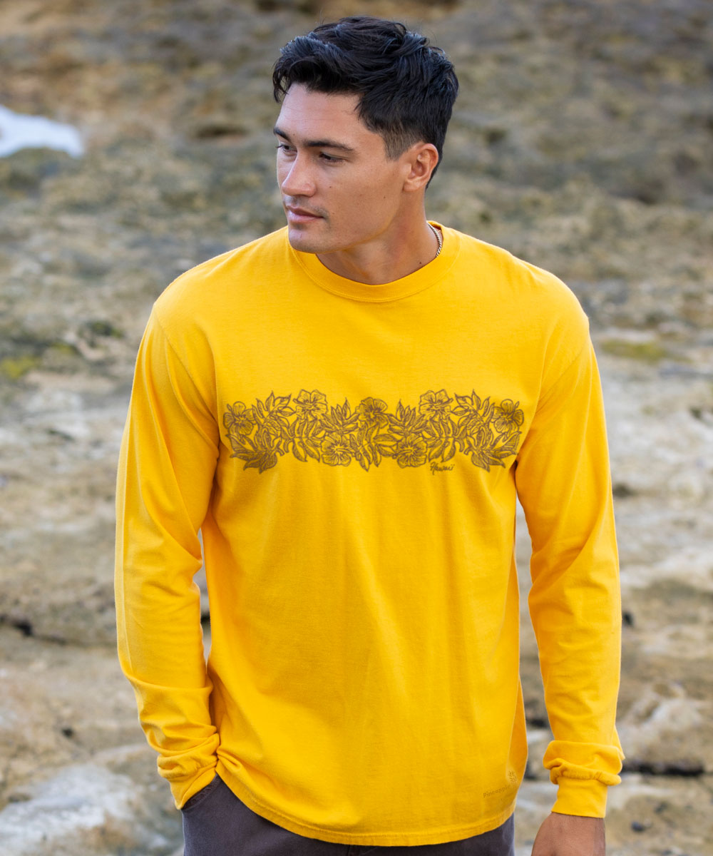 Man wearing a yellow long-sleeve shirt with a design on a rocky background View 2