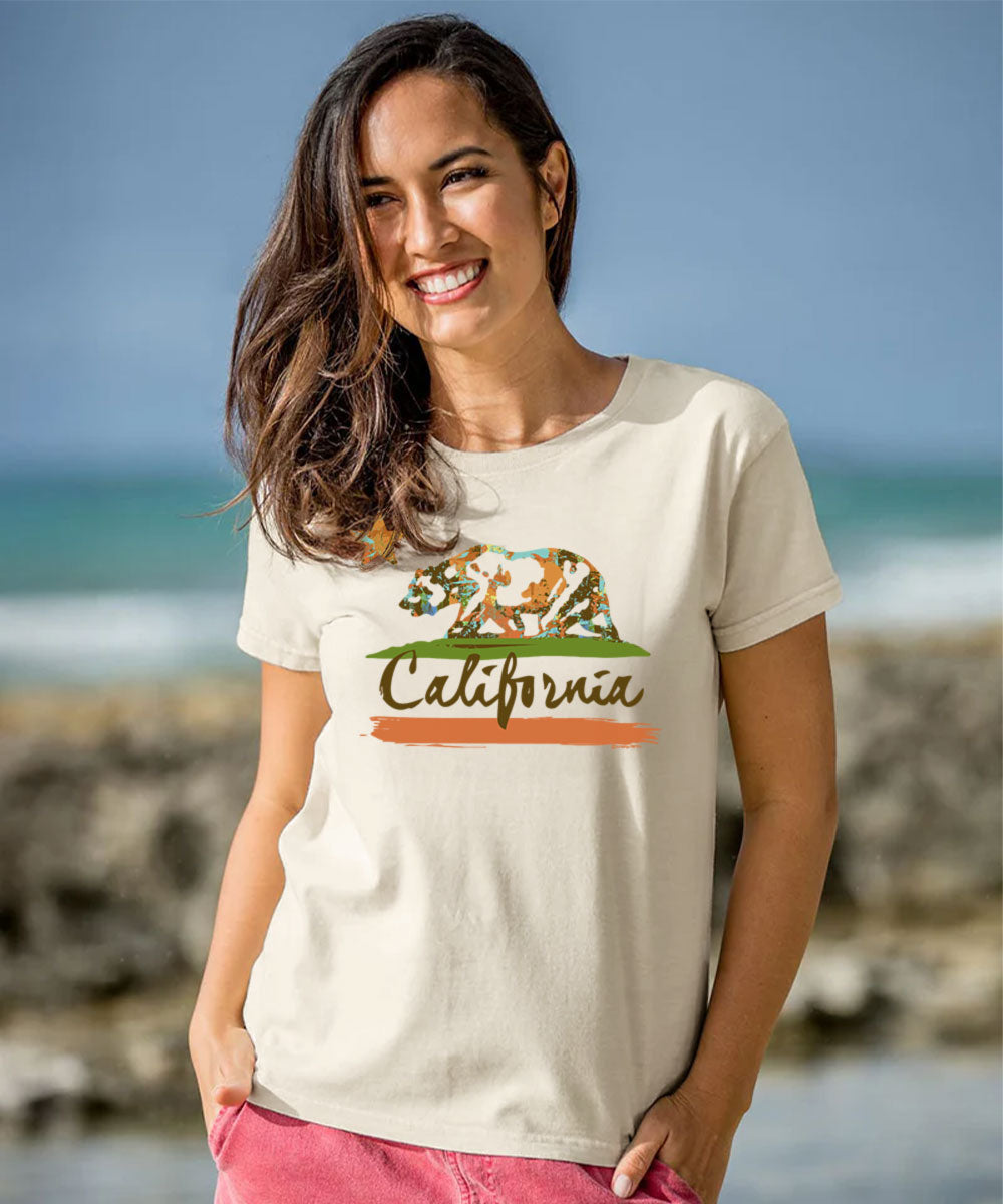 Woman wearing a white t-shirt with a California graphic design at the beach. View 2