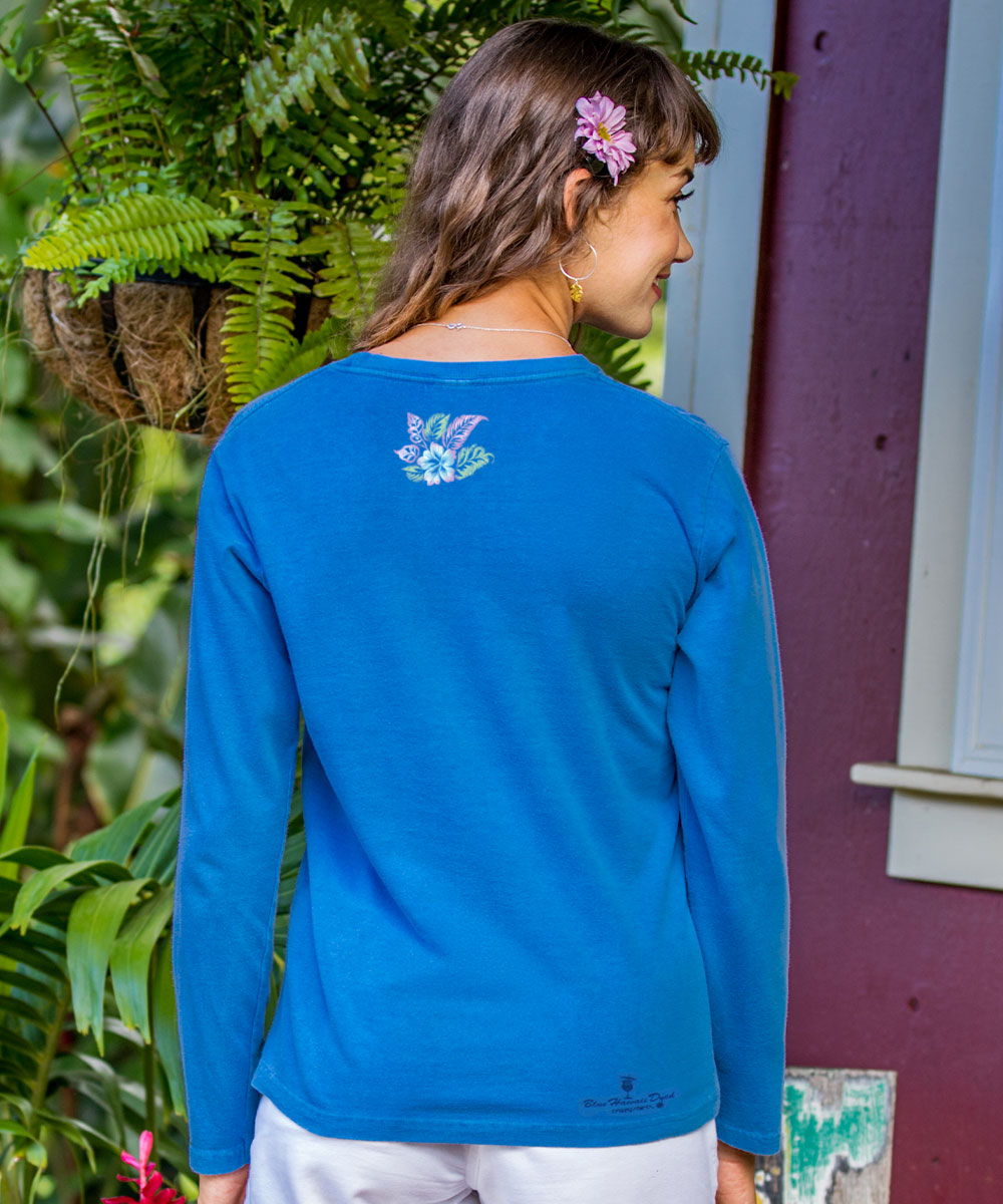 Woman wearing a blue long-sleeve shirt with a floral design on the back, standing outdoors. View 3